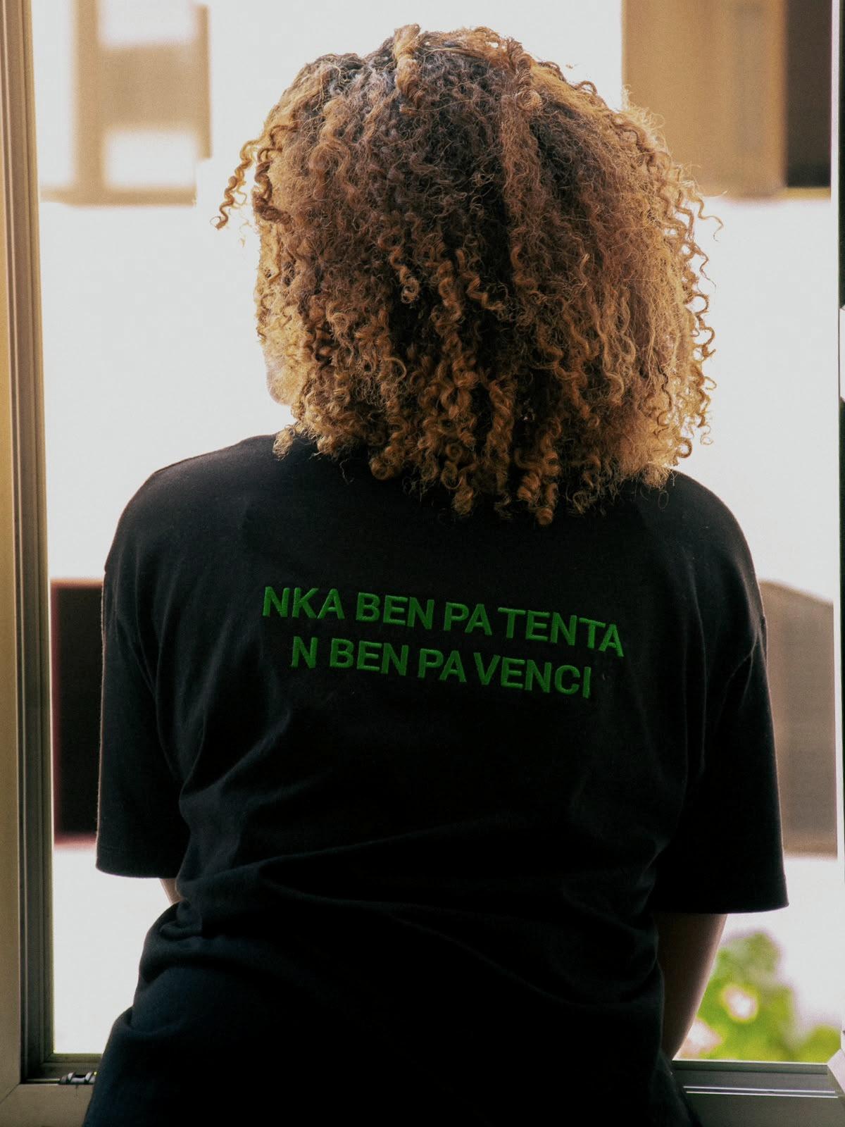From behind, in a t-shirt reading, in Kriolu, “Nka ben pa tenta, n ben pa venci”.