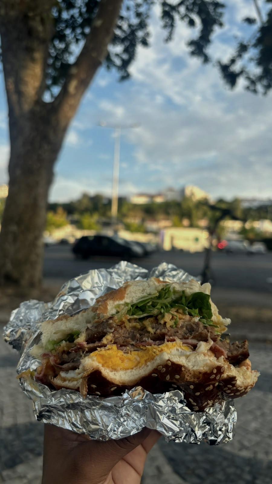 A foil-wrapped sandwich, at a table on the street.
